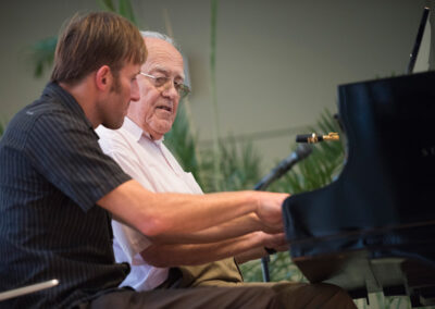 Ein Musiker mit einem Senior am Klavier