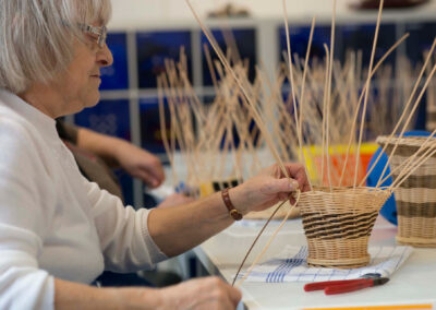 Eine Seniorin beim Korbflechten.
