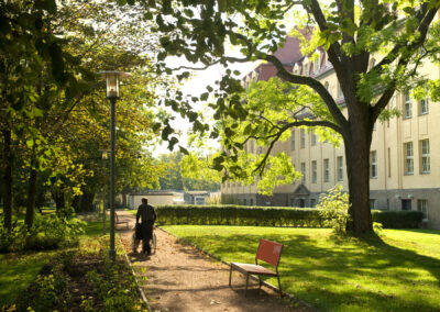 Ein Mann schiebt eine Person im Rollstuhl durch den Park.