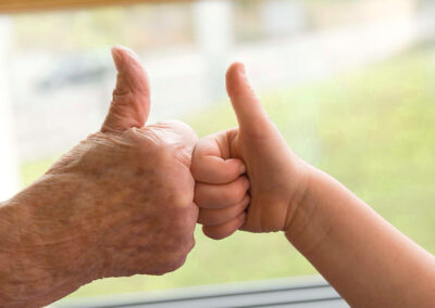 Zwei nach oben gestreckte Daumen von einem alten Menschen und einem Kind.